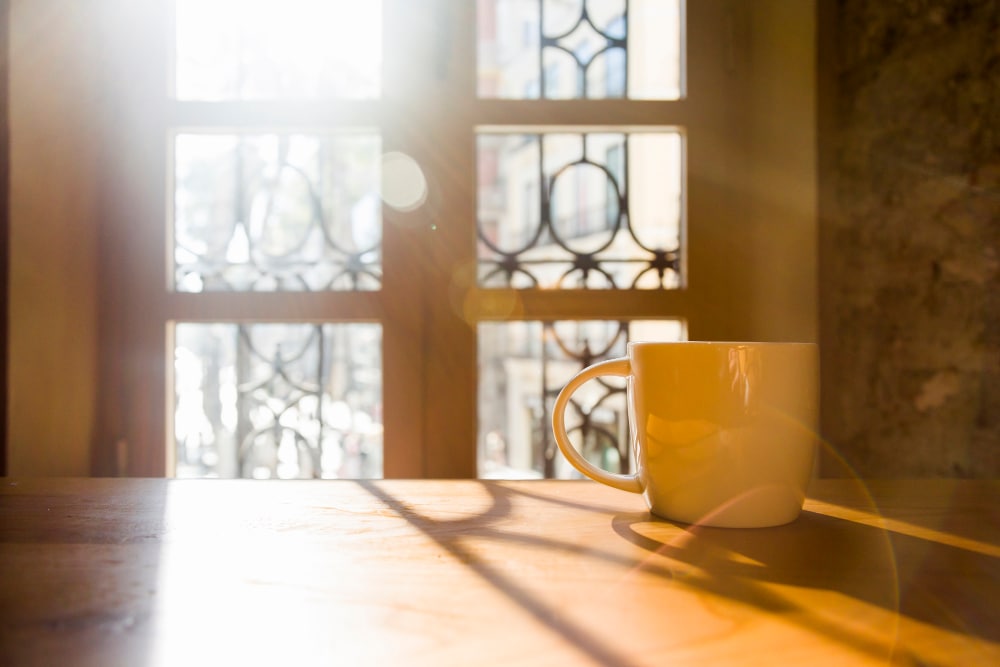 Eine Tasse Kaffee auf einem Holztisch vor einem Fenster.